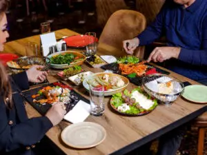 couple-have-dinner-with-pasta-salads-cheese-plate-pickles-olives