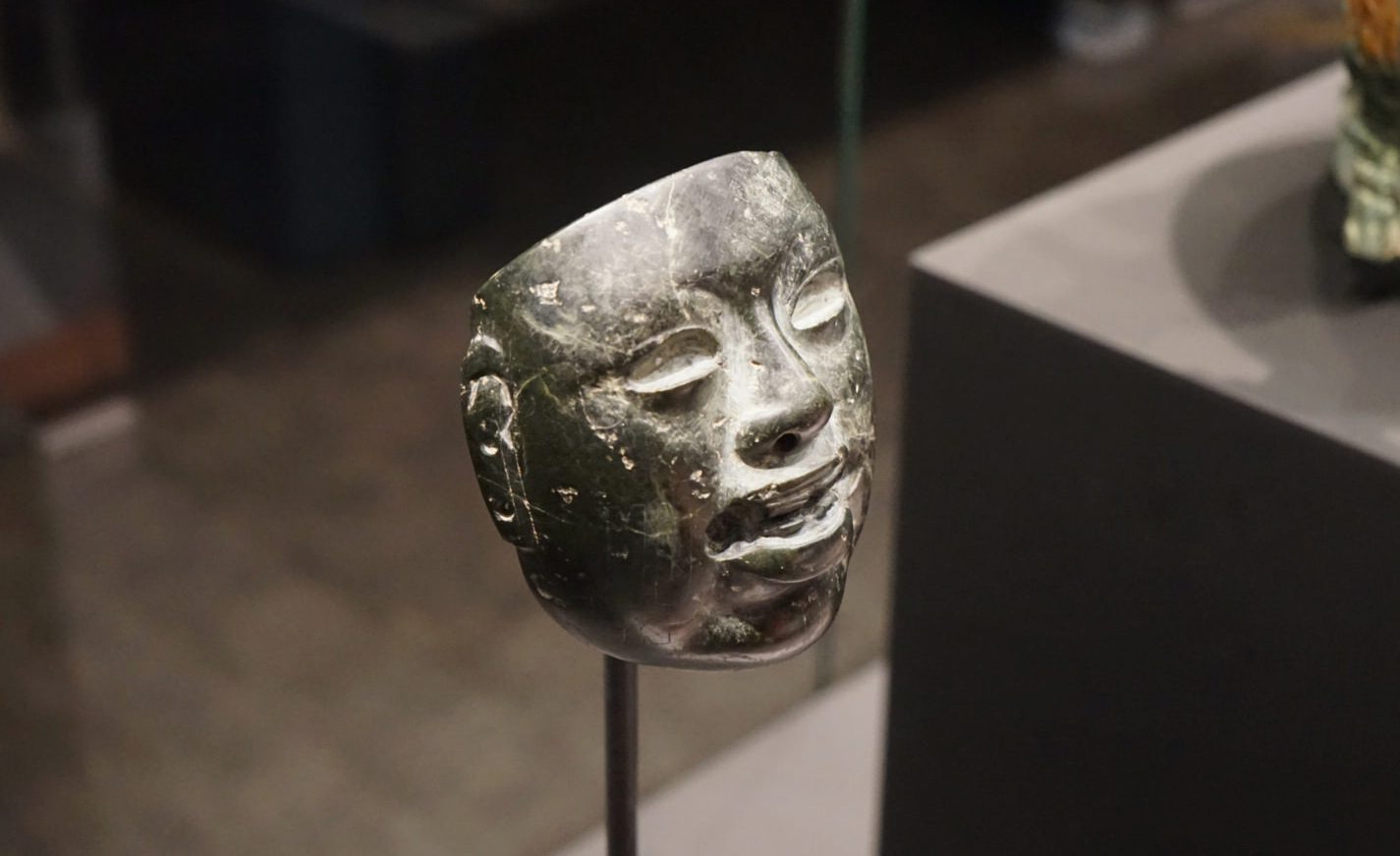 Close-up of the Ancient Mesoamerican Jade Mask at the British Museum, displaying intricate carvings and vibrant green jade craftsmanship.